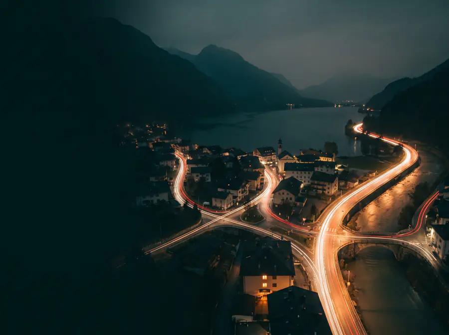 Langzeitbelichtung einer Stadt bei Nacht, viele Lichtspuren fliessen zu einem einzigen Lichtstrom zusammen.
